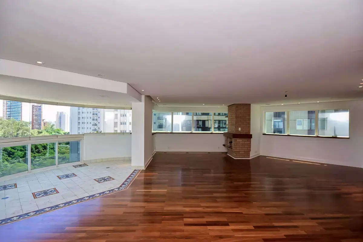 Varanda envidraçada integrada ao living com vista para o Parque Burle Marx. Conexão com a natureza: o living se estende até a varanda, revelando a copa das árvores do parque.